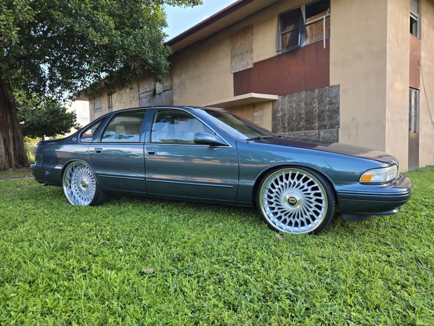 Blue classic Chevy-style sedan side profile on grass with polished wheels