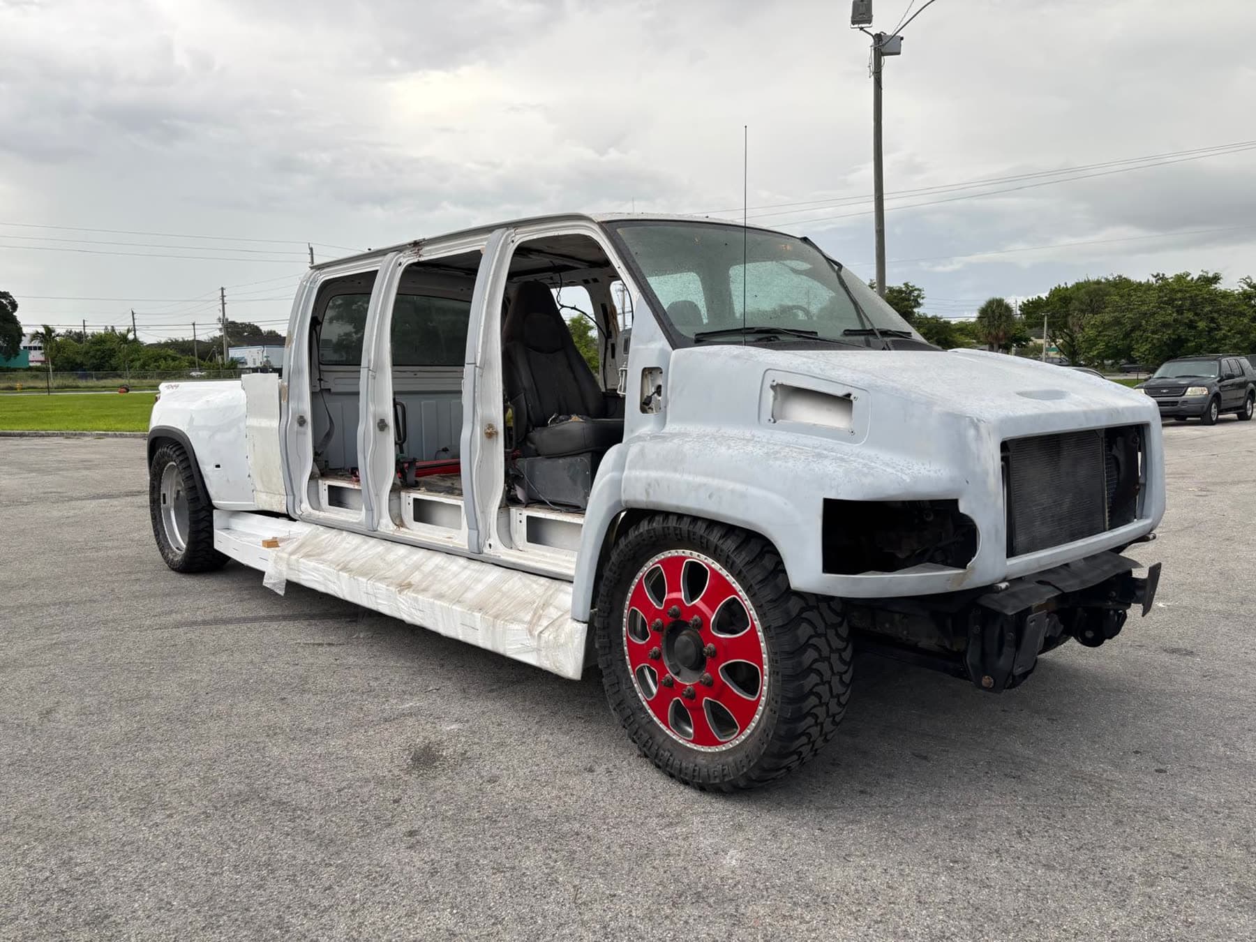 White Chevy dually project truck front three-quarter view with red wheel accents