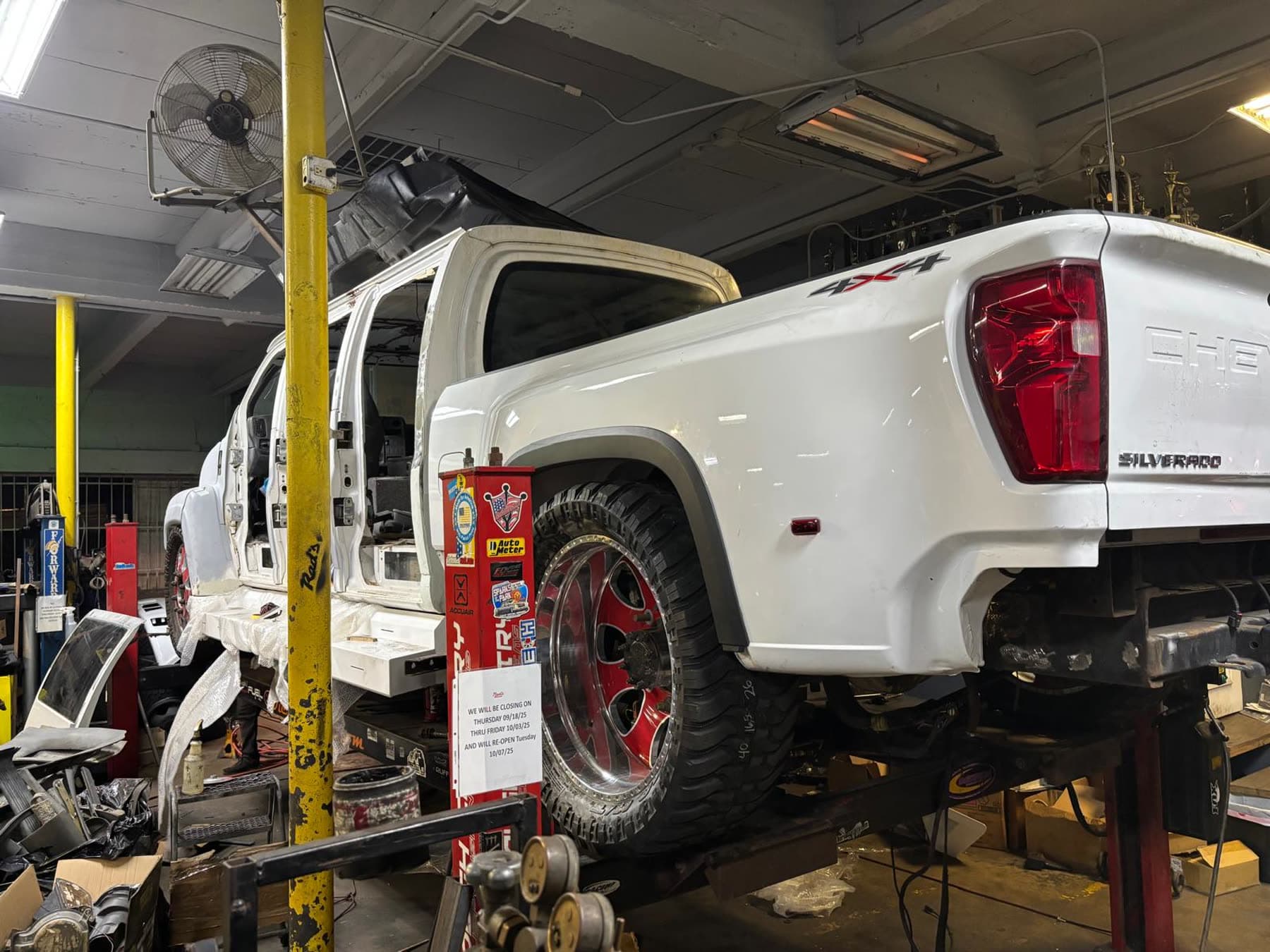 White dually truck inside the Diesel Wheels shop on a lift