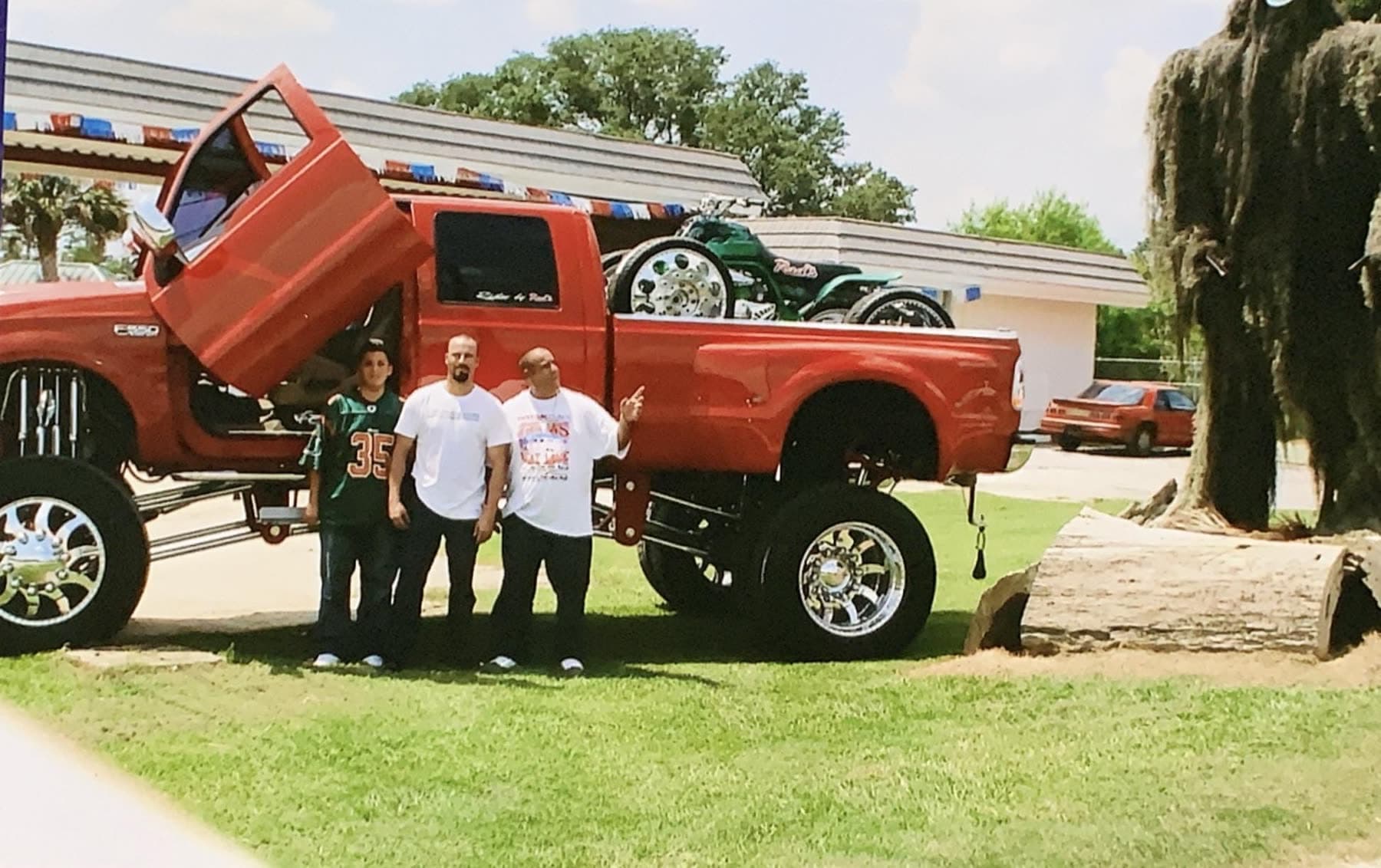 Red lifted dually truck with doors open and polished wheels