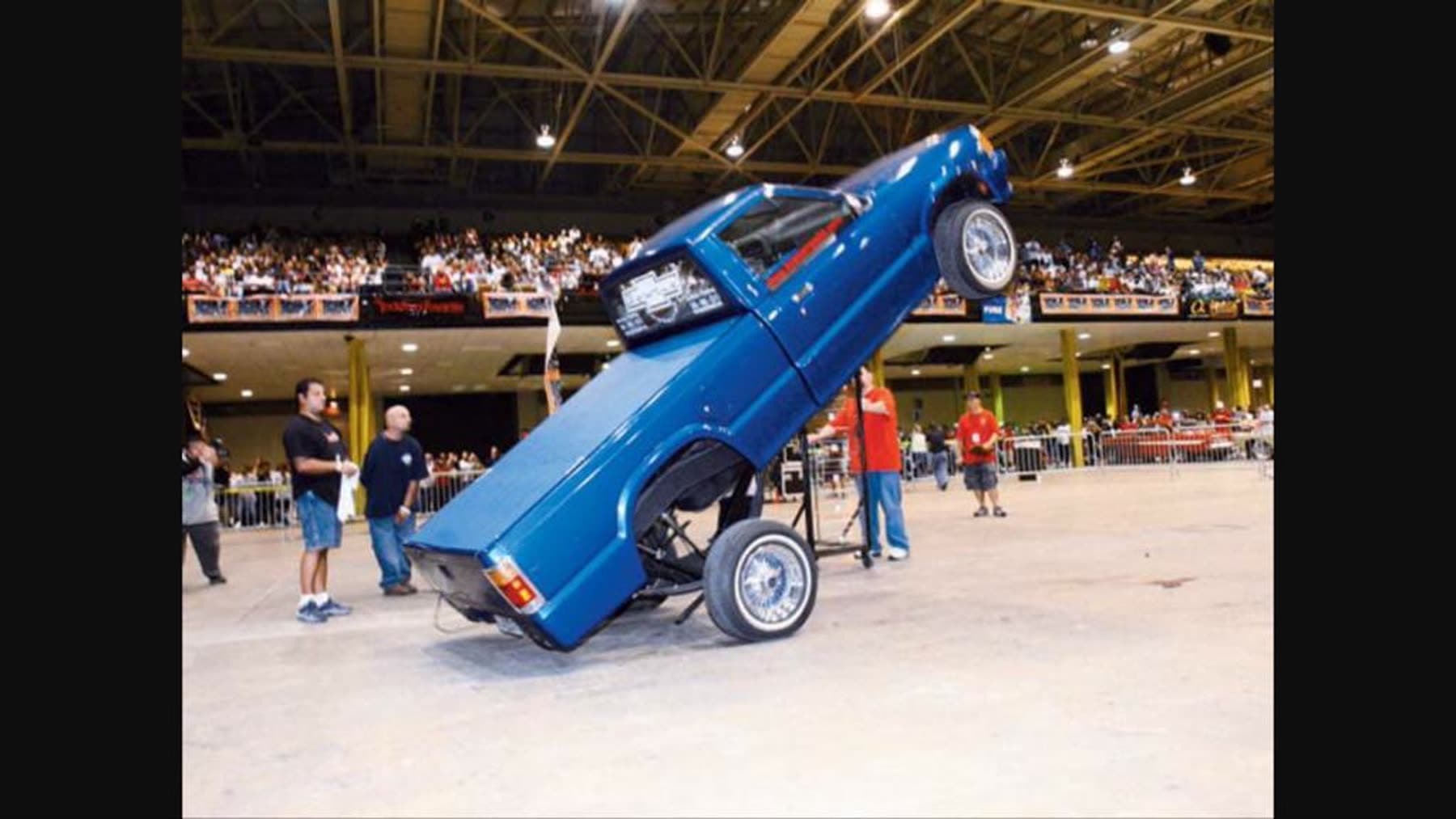 Blue custom truck doing a wheelstand at an event
